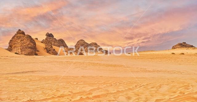 منظر صحراوي نموذجي في العلا، المملكة العربية السعودية، رمال تتخللها بعض الجبال، سيارة دفع رباعي صغيرة، وسماء برتقالية خلابة في الأعلى منظر صحراوي نموذجي في العلا، المملكة العربية السعودية، رمال تتخللها بعض الجبال، سيارة دفع رباعي صغيرة، وسماء برتقالية خلابة في الأعلى