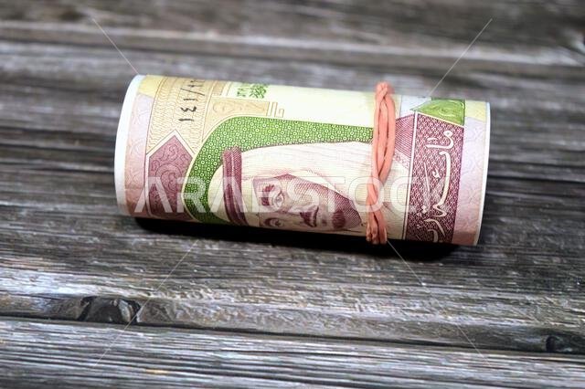 100 SAR one hundred Saudi Arabian riyals cash money banknote bills roll wrapped up with rubber band, features a portrait of king Fahd Bin AbdulAziz an