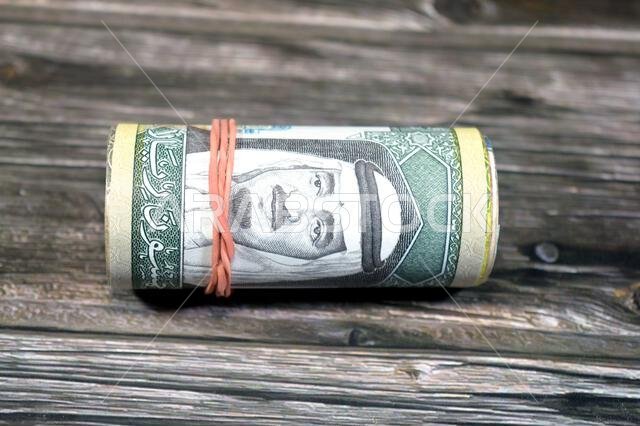 50 SAR fifty Saudi Arabian riyals cash money banknotes bills roll wrapped up with rubber band, features a portrait of king Fahd Bin AbdulAziz Al Saud 50 SAR fifty Saudi Arabian riyals cash money banknotes bills roll wrapped up with rubber band, features a portrait of king Fahd Bin AbdulAziz Al Saud