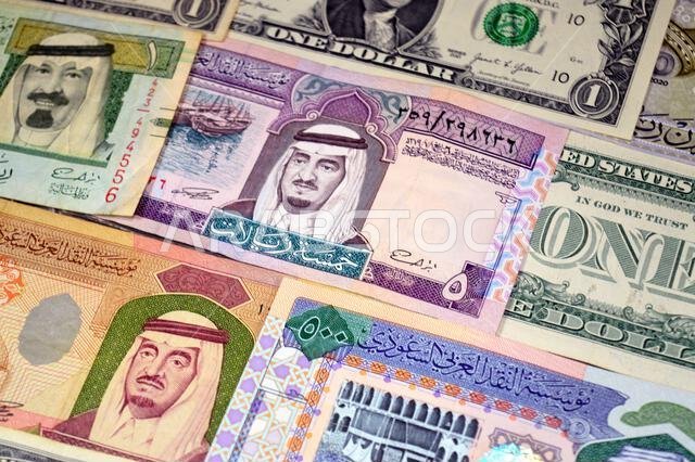 عملات ورقية من الدولارات الأمريكية والريال السعودي، من أزمنة وحقب وقيم مختلفة، عملات الريال السعودي والأمريكي