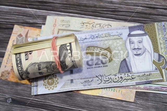 Saudi Arabian money SAR riyals bills and 50 USD fifty American dollars banknotes cash money rolled up with a rubber band, features Ulysses S. Grant, A