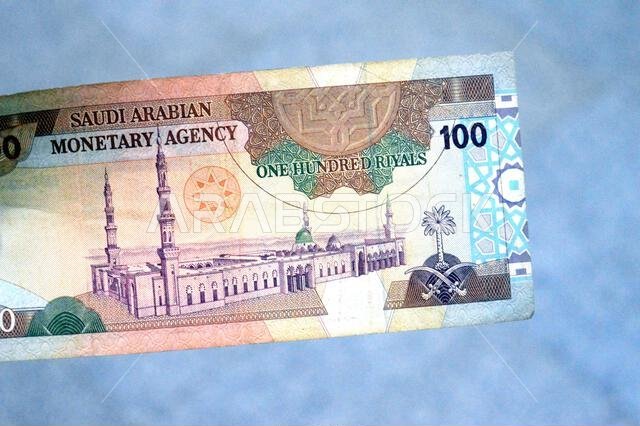 يُظهر الوجه الخلفي للورقة النقدية من فئة 100 ريال سعودي منظراً عاماً للمسجد النبوي الشريف في المدينة المنورة.
