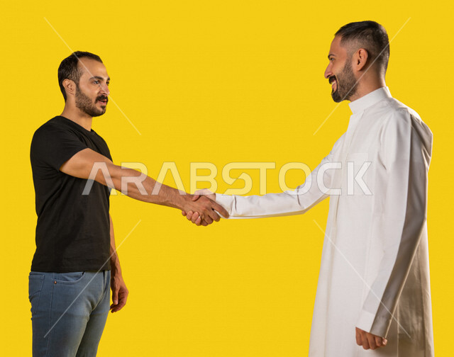 بورتريه لرجلان عربيان خليجيان سعوديان، العلاقات المترابطة، علاقات اجتماعية، تعارف وصداقات، اصدقاء يتصافحان بحرارة، ايماءات وجه ويدين تدل على السعادة الشديدة، خلفية صفراء