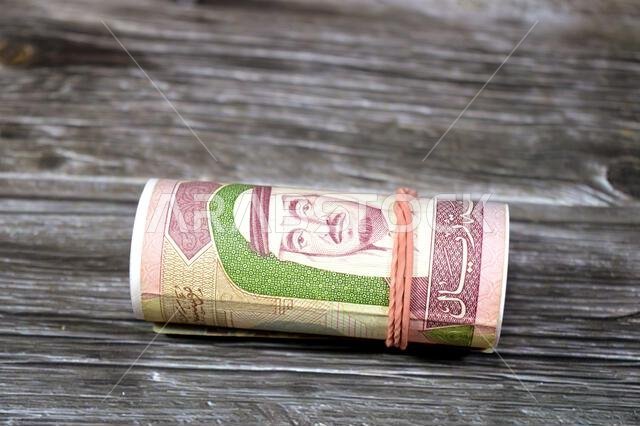 100 SAR one hundred Saudi Arabian riyals cash money banknote bills roll wrapped up with rubber band, features a portrait of king Fahd Bin AbdulAziz an