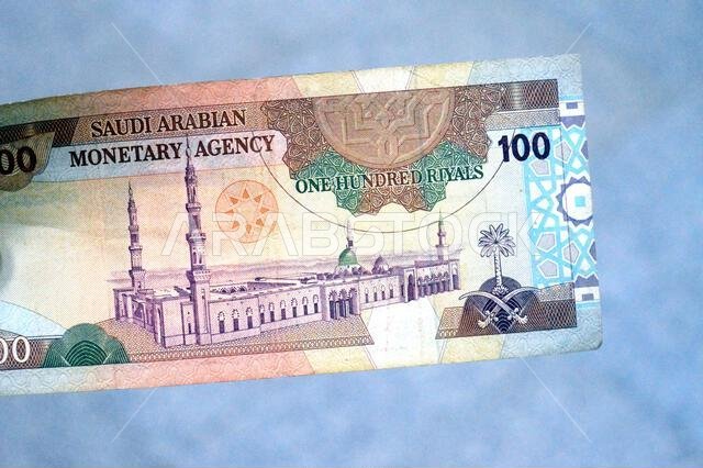 يُظهر الوجه الخلفي للورقة النقدية من فئة 100 ريال سعودي منظراً عاماً للمسجد النبوي الشريف في المدينة المنورة.