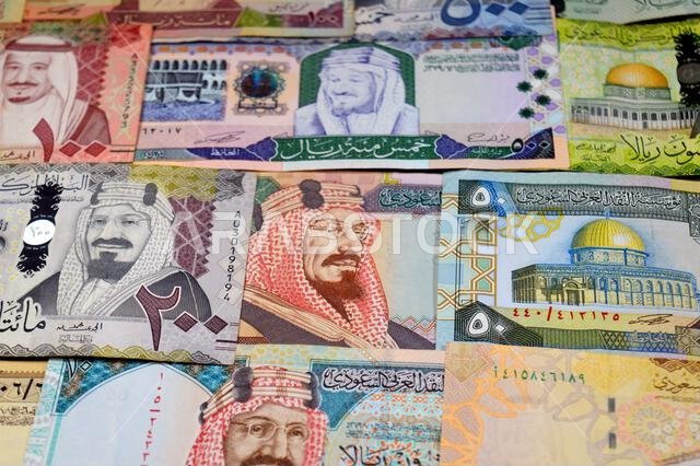 أوراق نقدية من الريال السعودي (SAR) من مختلف العصور والقيم، بدءًا من العملات القديمة ذات الطابع الكلاسيكي في عهد الملك فهد وحتى عهد الملك سلمان.