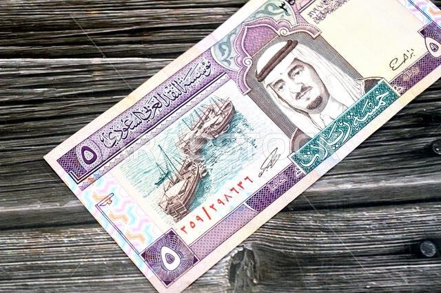 the obverse side of 5 SAR five Saudi Arabian riyals cash money banknote bill, features a portrait of king Fahd Bin AbdulAziz Al Saud and Dhows at lef the obverse side of 5 SAR five Saudi Arabian riyals cash money banknote bill, features a portrait of king Fahd Bin AbdulAziz Al Saud and Dhows at lef