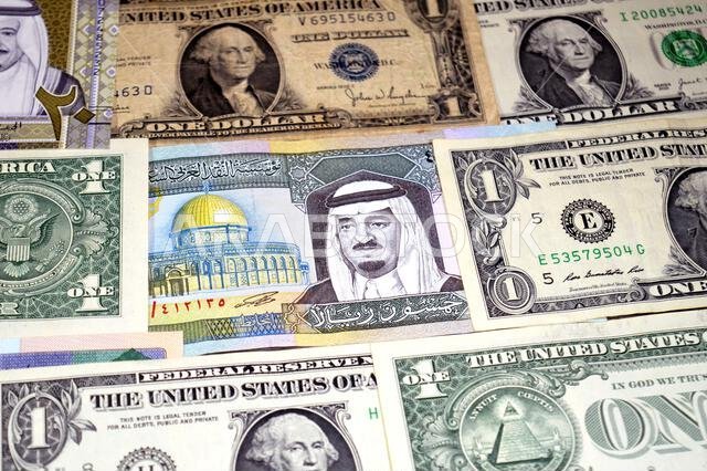 عملات ورقية من الدولارات الأمريكية والريال السعودي، من أزمنة وحقب وقيم مختلفة، عملات الريال السعودي والأمريكي