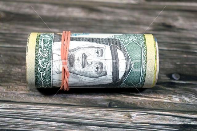 50 SAR fifty Saudi Arabian riyals cash money banknotes bills roll wrapped up with rubber band, features a portrait of king Fahd Bin AbdulAziz Al Saud 50 SAR fifty Saudi Arabian riyals cash money banknotes bills roll wrapped up with rubber band, features a portrait of king Fahd Bin AbdulAziz Al Saud