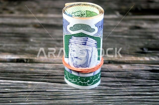 خمسمائة ريال سعودي، عبارة عن لفافة من الأوراق النقدية ملفوفة بمطاط مرن، تحمل صورة الكعبة المشرفة داخل المسجد الحرام بمكة المكرمة.