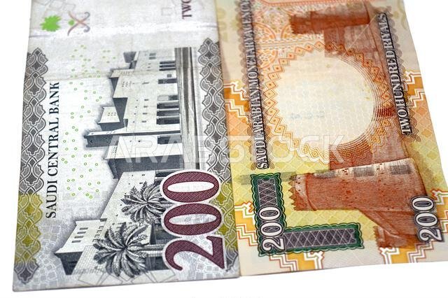 The reverse sides of old and new 200 SAR two hundred Saudi Arabia riyal cash money banknote bill, features Al Masmak Palace and the Qasr Al Hukm in Ri The reverse sides of old and new 200 SAR two hundred Saudi Arabia riyal cash money banknote bill, features Al Masmak Palace and the Qasr Al Hukm in Ri