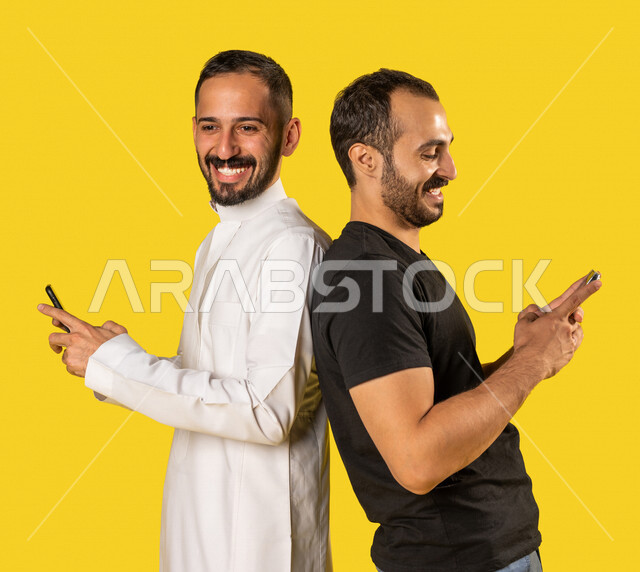 بورتريه لرجلان عربيان خليجيان سعوديان يستخدمان الهاتف المحمول، استخدام البرامج والتطبيقات الالكترونية، التسوق الالكتروني، التواصل الاجتماعي، تصفح المواقع الالكترونية، ادمان الانترنت، خلفية صفراء
