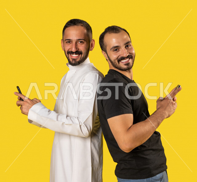 بورتريه لرجلان عربيان خليجيان سعوديان يستخدمان الهاتف المحمول، استخدام البرامج والتطبيقات الالكترونية، التسوق الالكتروني، التواصل الاجتماعي، تصفح المواقع الالكترونية، ادمان الانترنت، خلفية صفراء