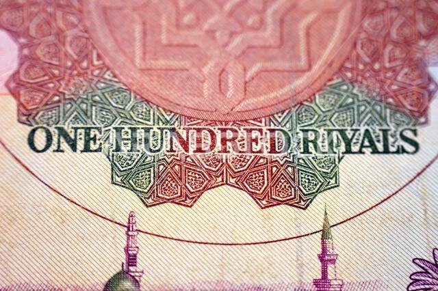 يُظهر جزء من الوجه الخلفي لورقة نقدية من فئة 100 ريال سعودي منظرًا عامًا للمسجد النبوي الشريف في