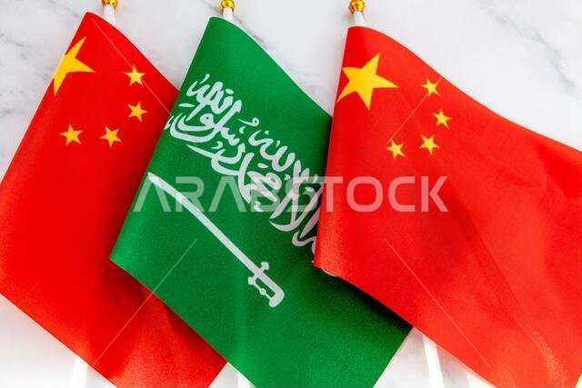 The national flag of Saudi Arabia on flag pole in between the Chinese national flag. A China, Saudi Arabia relations concept.