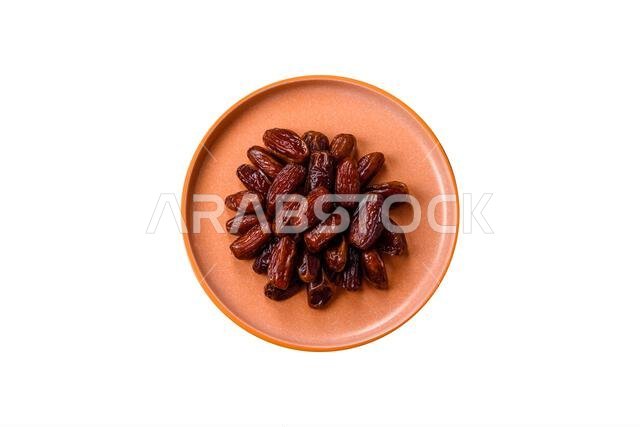 Dried dates in a ceramic plate, arabic food for the ramadan table. Dried dates as a food backdrop for your design.
