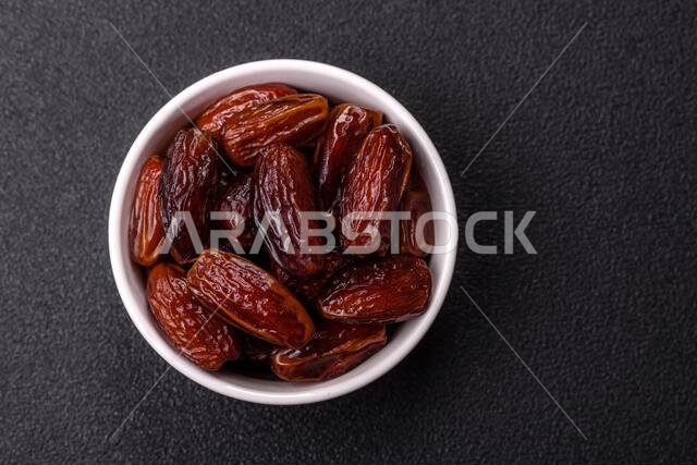 Dried dates in a ceramic plate, arabic food for the ramadan table. Dried dates as a food backdrop for your design.