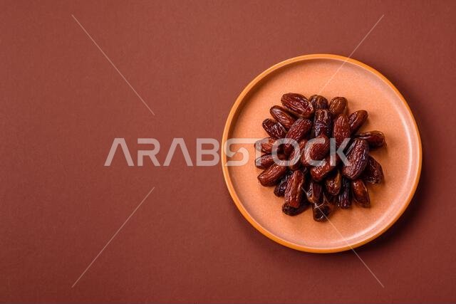 Dried dates in a ceramic plate, arabic food for the ramadan table. Dried dates as a food backdrop for your design.