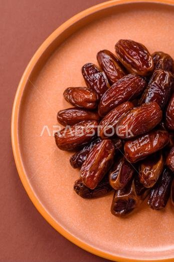 Dried dates in a ceramic plate, arabic food for the ramadan table. Dried dates as a food backdrop for your design.