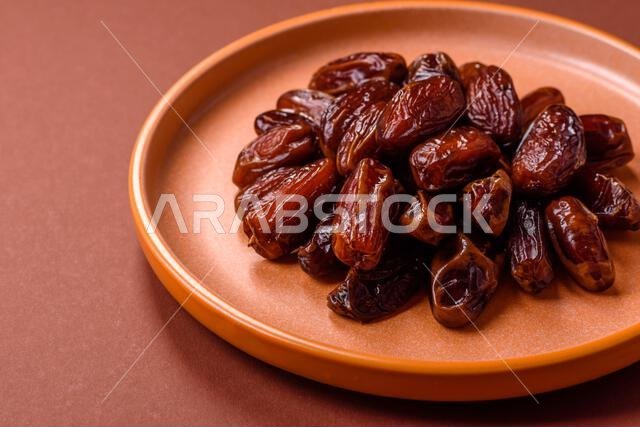 Dried dates in a ceramic plate, arabic food for the ramadan table. Dried dates as a food backdrop for your design.