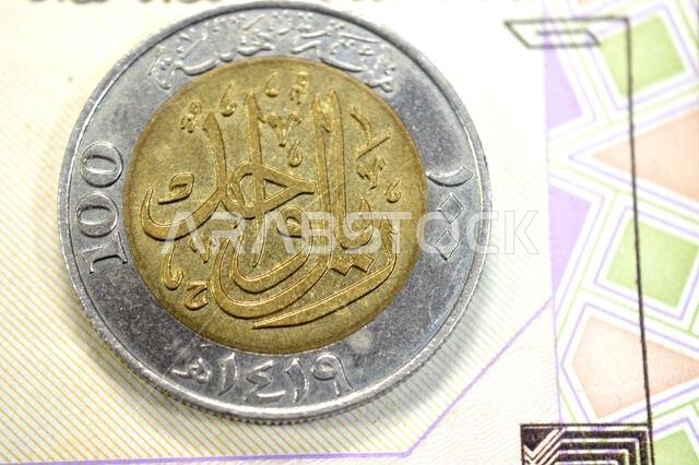 The reverse side of 1 SAR one Saudi Arabian Riyal coin features Denomination, Lettering, One Hundred Halalah, One Riyal 1419, on an old vintage retro