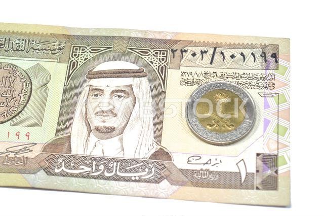 يحمل وجه العملة المعدنية من فئة ريال سعودي واحد (1 ريال سعودي) الشعار الوطني في المنتصف، مع كتابة "خادم الحرمين الشريفين" حوله.