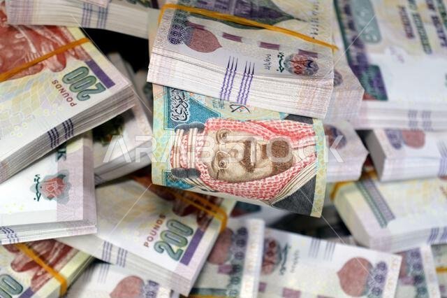 ريال سعودي وأكوام من النقود المصرية بقيمة 200 جنيه مصري، صادرة عن البنك المركزي المصري.