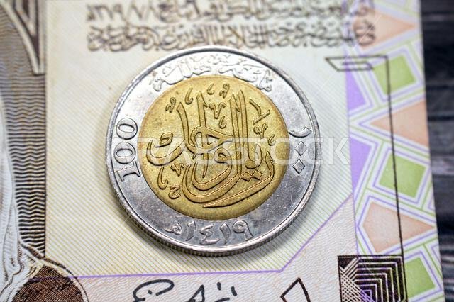 يحتوي الوجه الخلفي لعملة الريال السعودي الواحد (1 ريال سعودي) على القيمة الاسمية، والكتابة، وعبارة "مائة هلالة"، و"ريال واحد 1419"، على تصميم عتيق قديم.