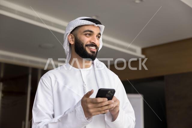 رجل أعمال عربي سعيد وناجح يستخدم هاتفه المحمول