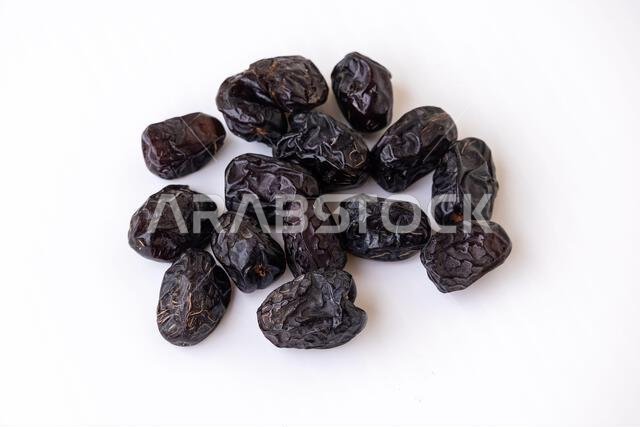 Sweet and nutritious Ajwa dates, the Holy Fruit of Madinah, isolated on white background. Organic, healthy dessert or snack. High in fiber, whole food