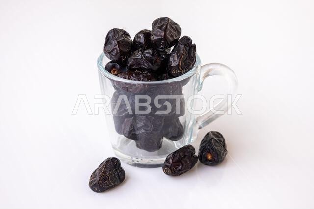 Delicious, healthy, and organic Ajwa dates, a premium Arabic fruit, neatly arranged in a clear glass cup. Nutritious energy food, perfect for Ramadan Delicious, healthy, and organic Ajwa dates, a premium Arabic fruit, neatly arranged in a clear glass cup. Nutritious energy food, perfect for Ramadan