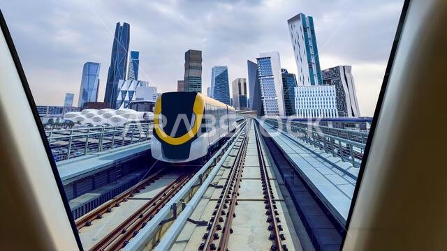 Riyadh Metro Yellow Line train passing with the King Abdullah Financial District skyline in the background on a cloudy day in Riyadh, Saudi Arabia.