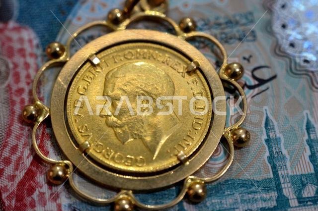 SAR Saudi Arabian riyals money and obverse side of King George V gold sovereign coin, features a left-facing portrait of King George V, sovereigns are