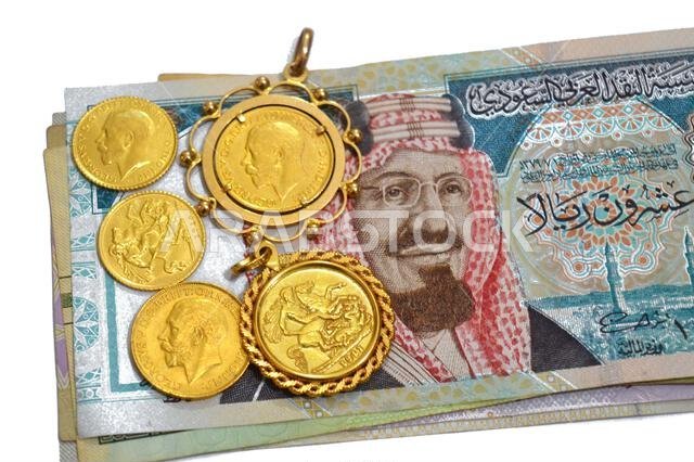 Saudi Arabian riyals money banknote bills and King George V gold sovereign coins, features King George V and the classic St. George and the Dragon, SA