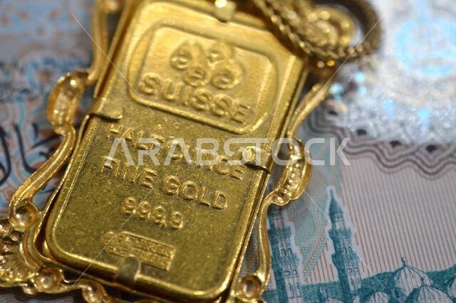 Cairo, Egypt, October 29 2025: A closeup of a PAMP Suisse gold bar pendant on SAR Saudi Arabian riyals money, 24K Gold Bar Half Ounce 15.55 Grams, pur