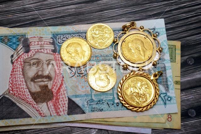 Saudi Arabian riyals money banknote bills and King George V gold sovereign coins, features King George V and the classic St. George and the Dragon, SA Saudi Arabian riyals money banknote bills and King George V gold sovereign coins, features King George V and the classic St. George and the Dragon, SA