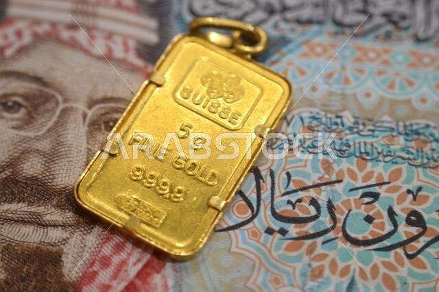 القاهرة، مصر، 29 أكتوبر 2025: صورة مقرّبة لعملة الريال السعودي وقلادة من الذهب عيار 24 قيراطًا من شركة بامب سويس، وزنها 5 غرامات.