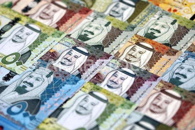 أوراق نقدية من الريال السعودي مكدسة في كومة كبيرة على طاولة، صورة مقرّبة. مفهوم التمويل والأعمال في المملكة العربية السعودية