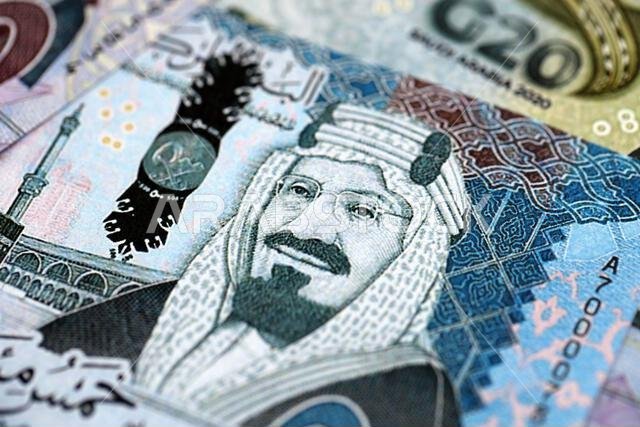 Saudi Arabia riyal money bills banknotes lies in big pile on table close up. Concept of finances and business in Saudi Arabia
