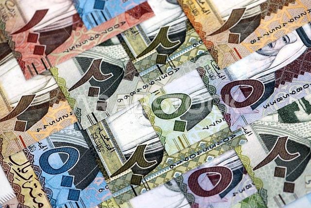 أوراق نقدية من الريال السعودي مكدسة في كومة كبيرة على طاولة، صورة مقرّبة. مفهوم التمويل والأعمال في المملكة العربية السعودية