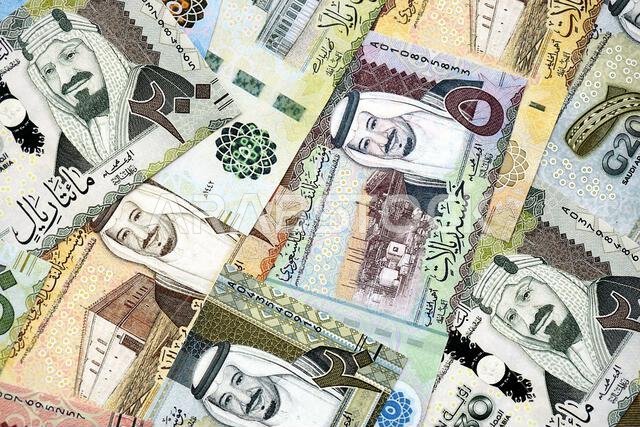 Saudi Arabia riyal money bills banknotes lies in big pile on table close up. Concept of finances and business in Saudi Arabia