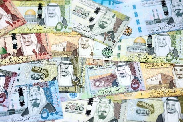 Saudi Arabia riyal money bills banknotes lies in big pile on table close up. Concept of finances and business in Saudi Arabia
