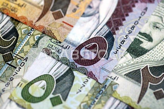 Saudi Arabia riyal money bills banknotes lies in big pile on table close up. Concept of finances and business in Saudi Arabia