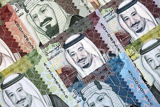 Saudi Arabia riyal money bills banknotes lies in big pile on table close up. Concept of finances and business in Saudi Arabia