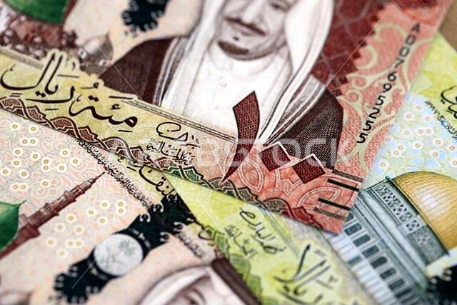 Saudi Arabia riyal money bills banknotes lies in big pile on table close up. Concept of finances and business in Saudi Arabia