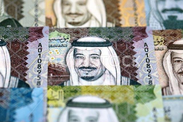 أوراق نقدية من الريال السعودي مكدسة في كومة كبيرة على طاولة، صورة مقرّبة. مفهوم التمويل والأعمال في المملكة العربية السعودية