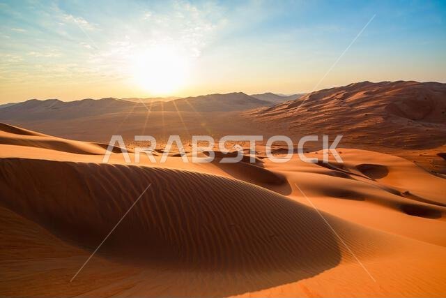 Rub' al-Khali (Empty Quarter) desert in Thumrayt, Dhofar, Oman, presenting sprawling orange sand dunes and a small settlement at the foot of distant