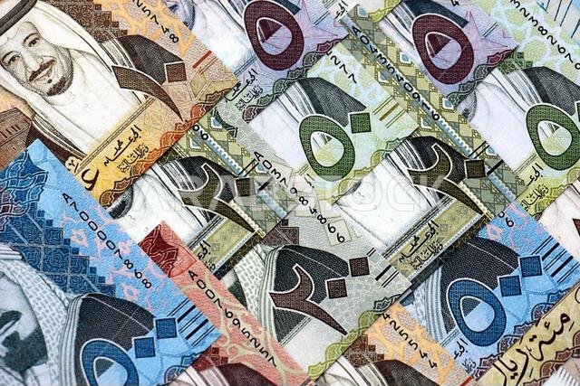 Saudi Arabia riyal money bills banknotes lies in big pile on table close up. Concept of finances and business in Saudi Arabia