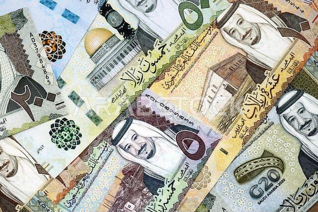 Saudi Arabia riyal money bills banknotes lies in big pile on table close up. Concept of finances and business in Saudi Arabia