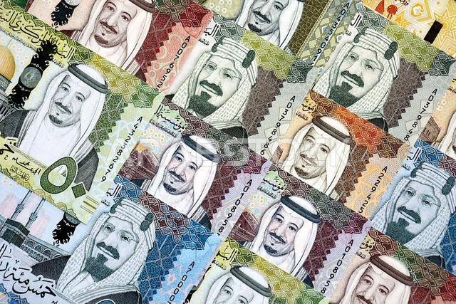 Saudi Arabia riyal money bills banknotes lies in big pile on table close up. Concept of finances and business in Saudi Arabia